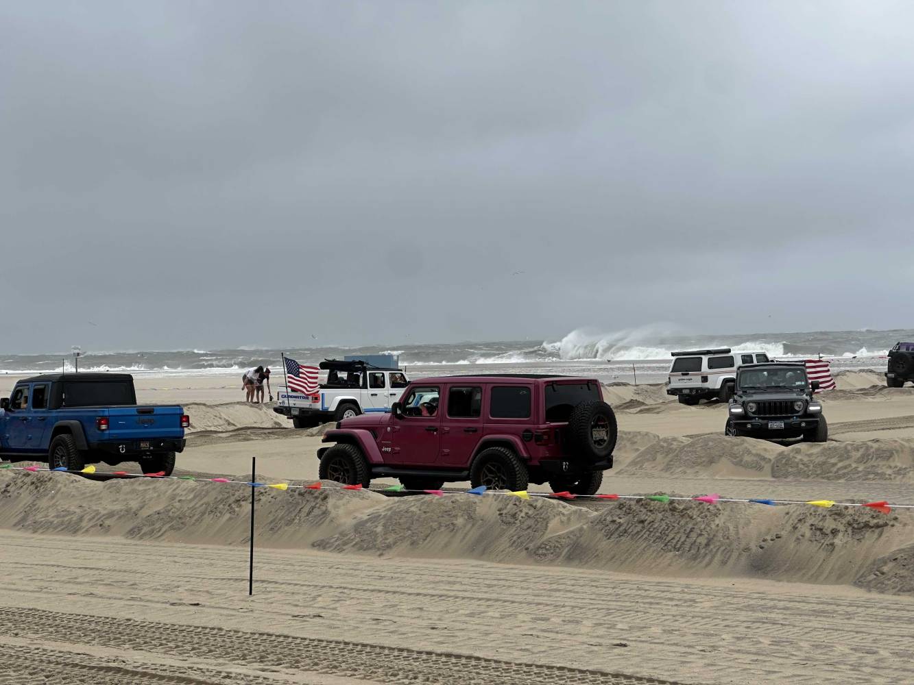 jeeps on the beach with big waves in the background