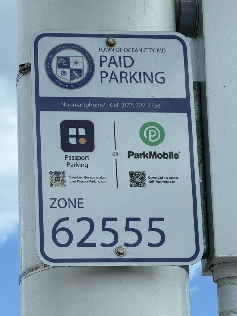 Paid parking sign in Ocean City, MD: Zone 62555, with Passport Parking and ParkMobile options and QR codes.